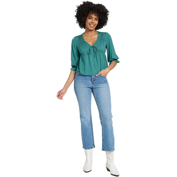 Close up view of the lightweight, flowy V neck ruffle blouse showing intricate stitching and soft fabric texture against a white background.