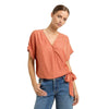 Front view of a model wearing the Emily Surplice Short Sleeve Top in Maple, showing dolman sleeves and a cinched hem, styled with high waisted jeans against a white background.