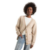 A model showcases a relaxed fit V neck cardigan in Heather Cream color, styled with high waisted jeans against a white background.