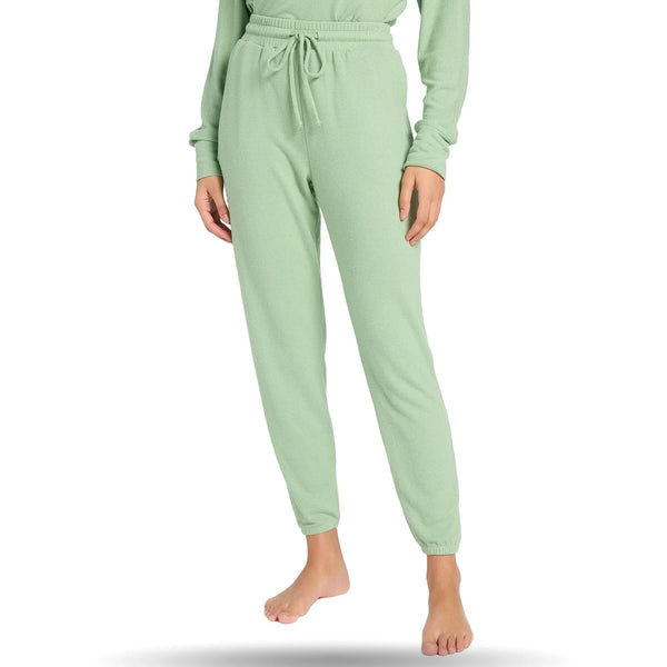 Woman wearing light green joggers with drawstring waist, standing barefoot on a white background