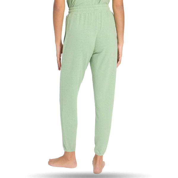 Woman wearing light green joggers, standing barefoot, view showing elastic waistband and tapered legs